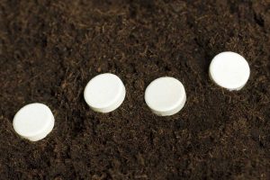 White aspirin tablets in brown soil.