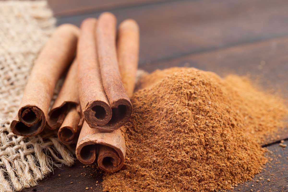 Cinnamon sticks and powder on brown wooden board.