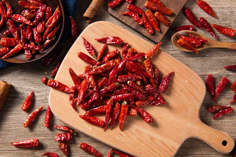 Dry, red hot chili peppers on a wooden cutting board.